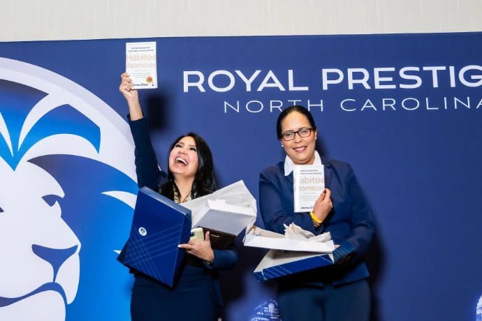 Representantes frente al logo de Royal Prestige en convención anual."
