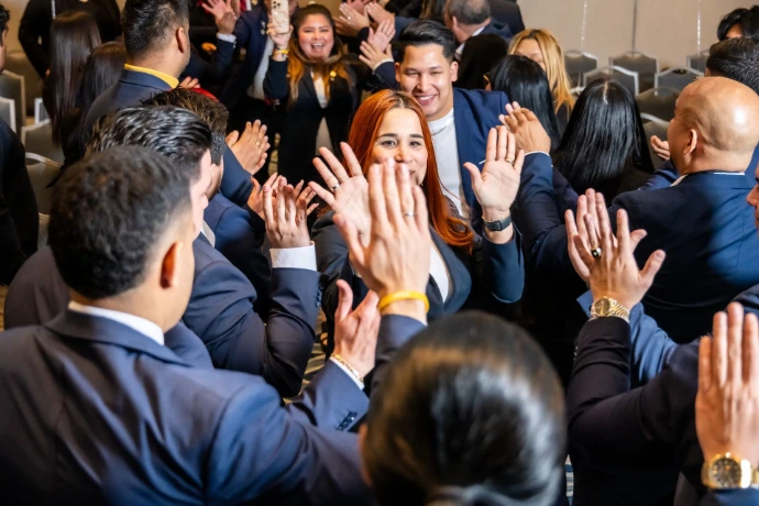 Audiencia aplaudiendo durante presentación magistral en convención de ventas