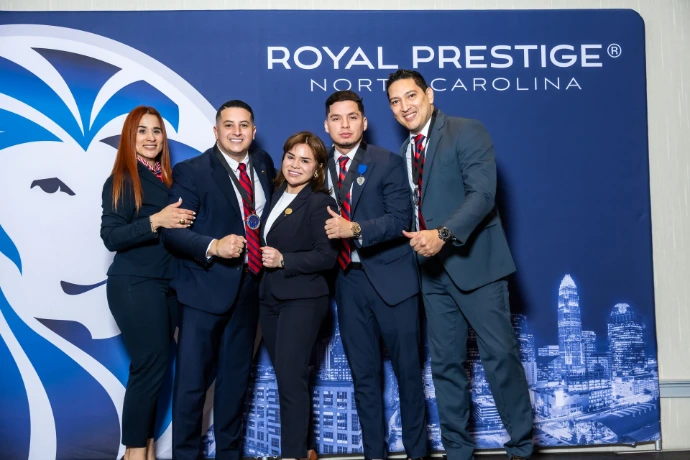 Representantes frente al logo de Royal Prestige en convención anual."